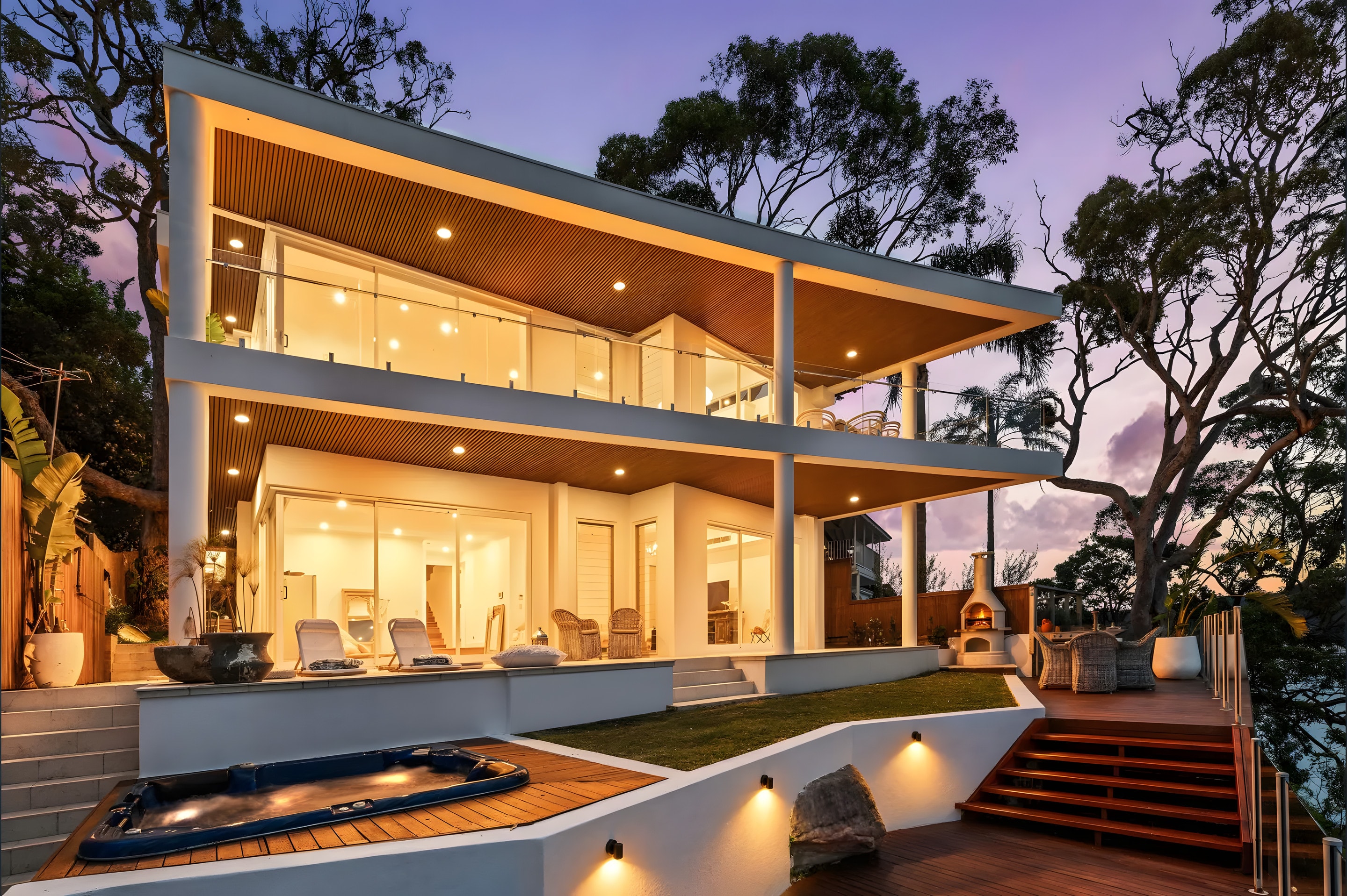 A two-storey home with lit terraces at dusk