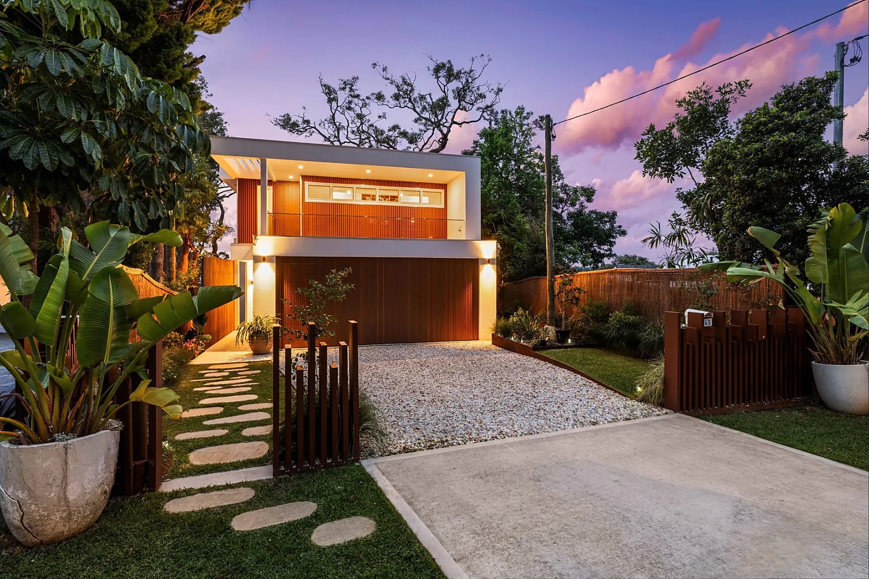 A timber-clad home and garden path at dusk