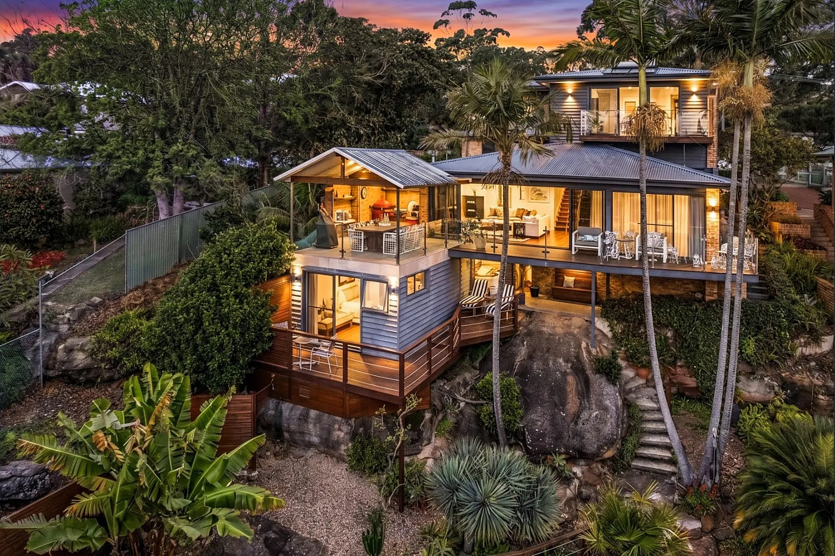 A hillside home among palms at dusk