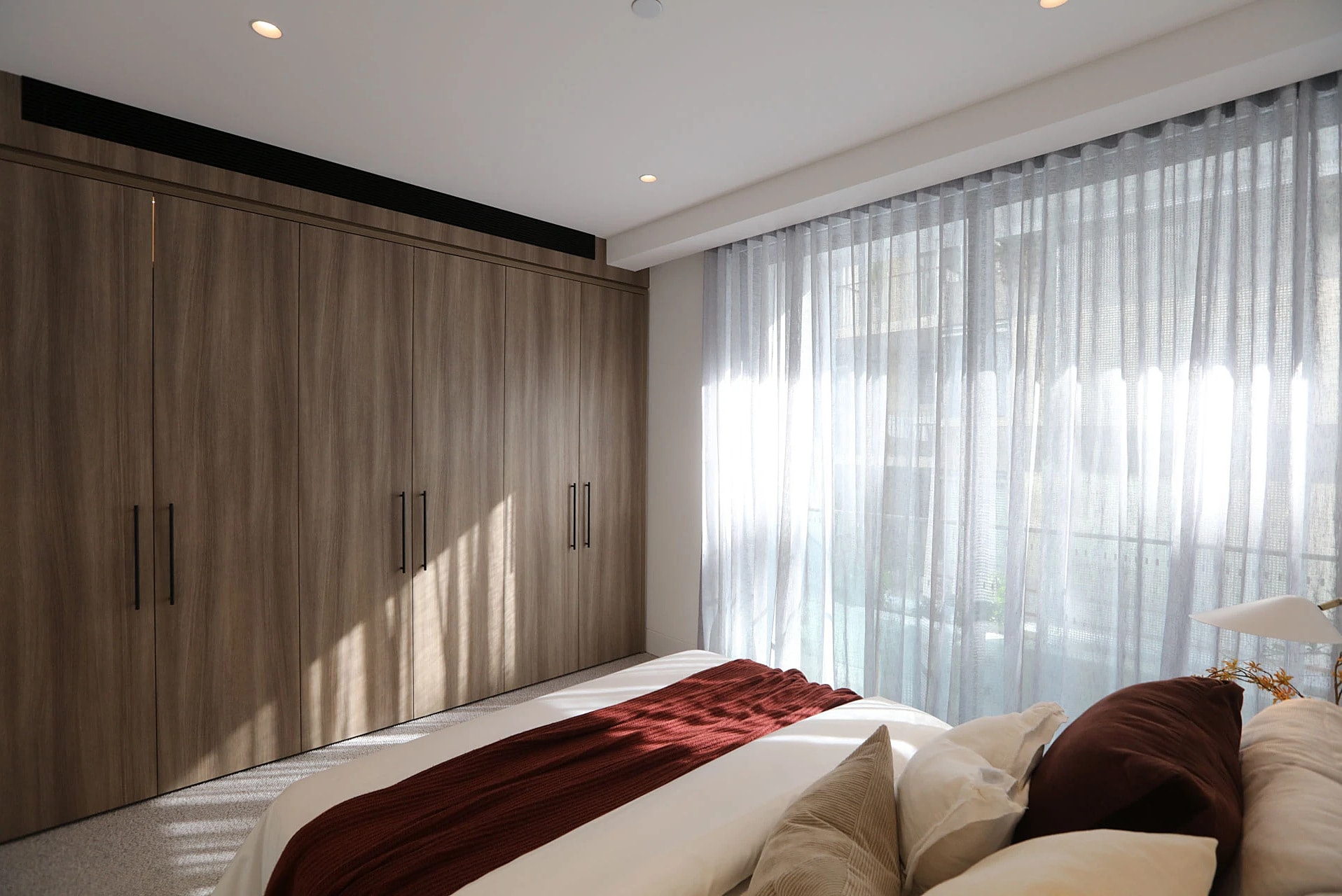 Bedroom with timber joinery and sheer curtains