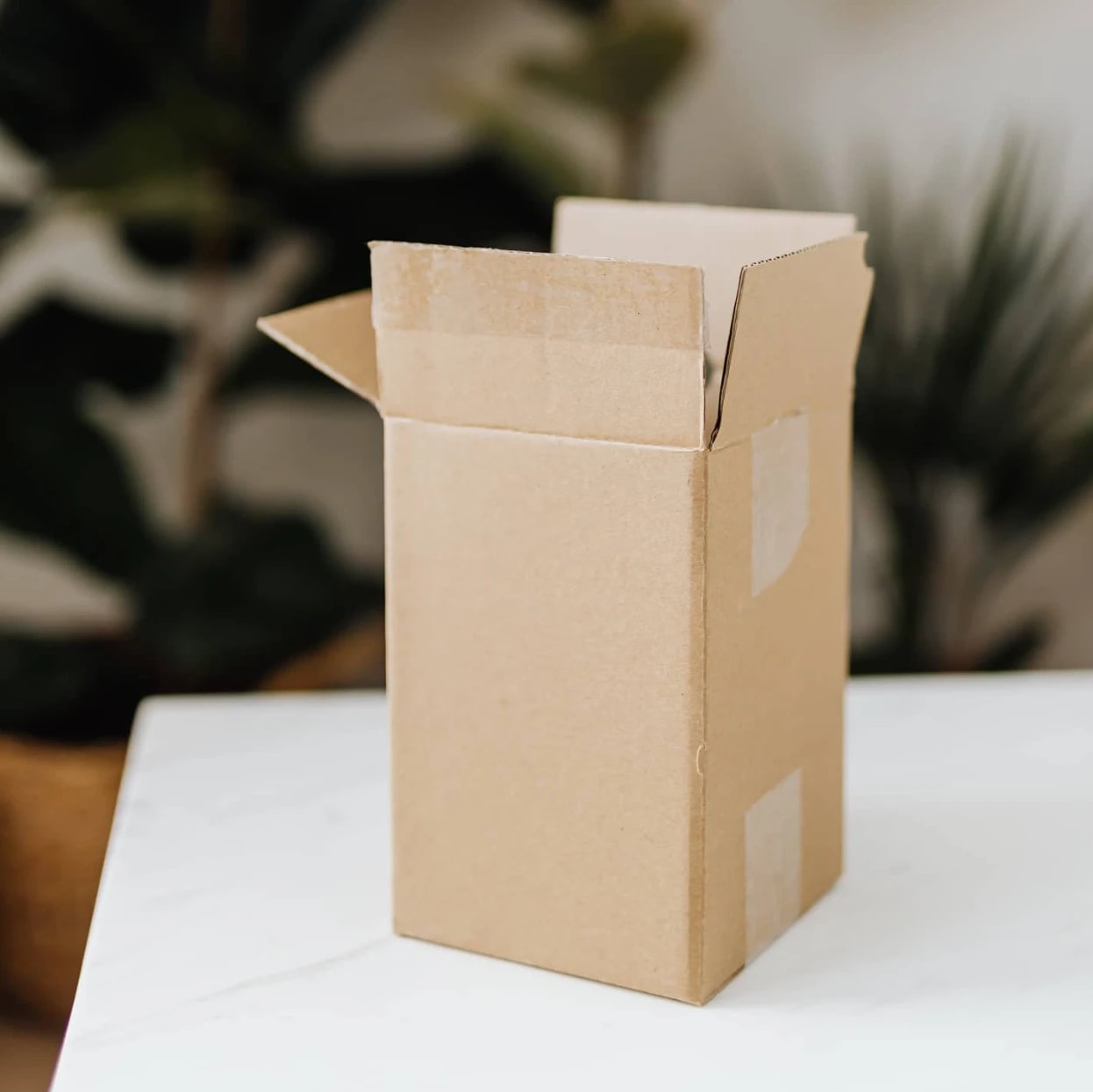 An open kraft shipping box on a marble table
