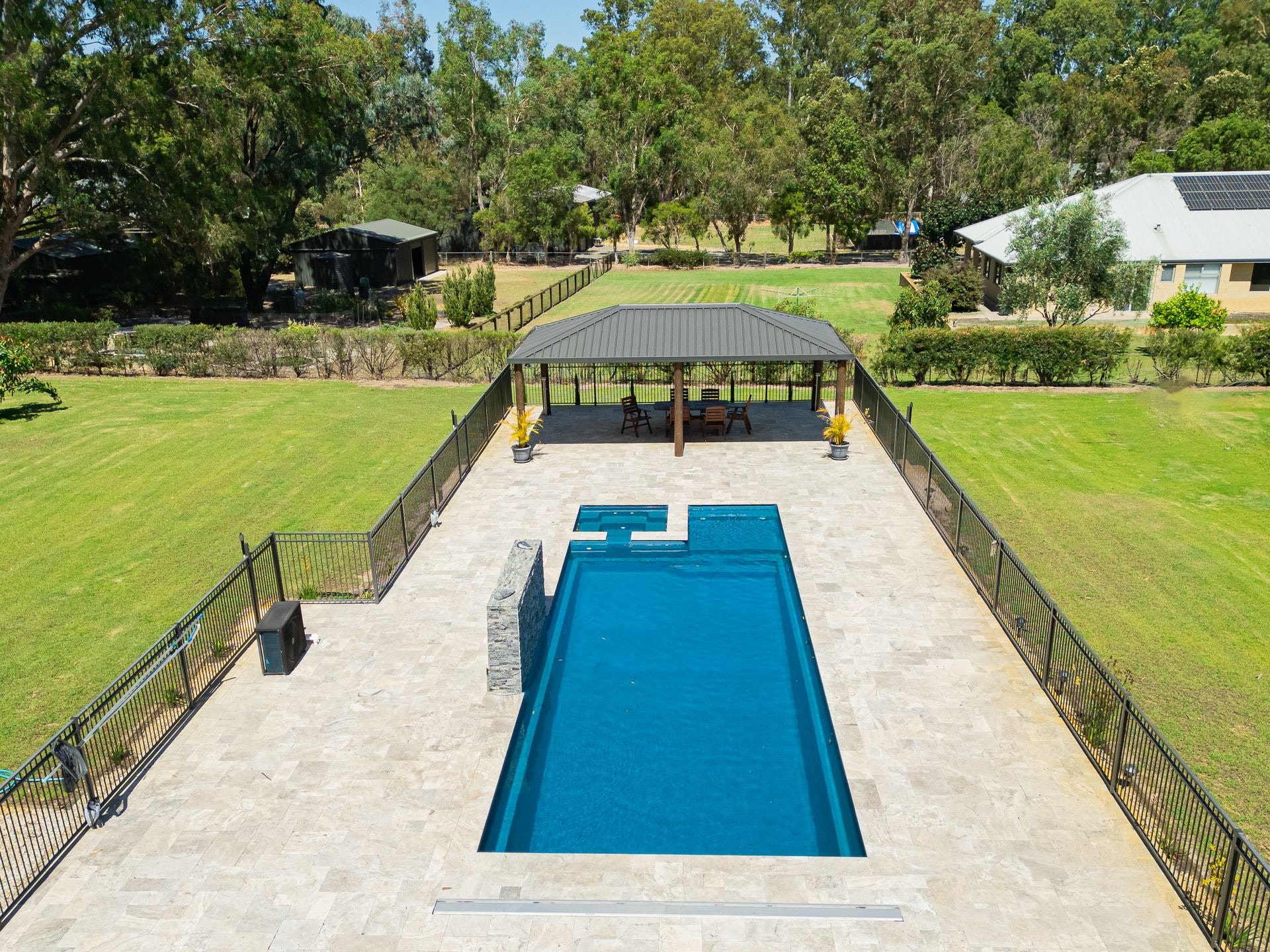 Aerial view of a long pool with a pavilion behind