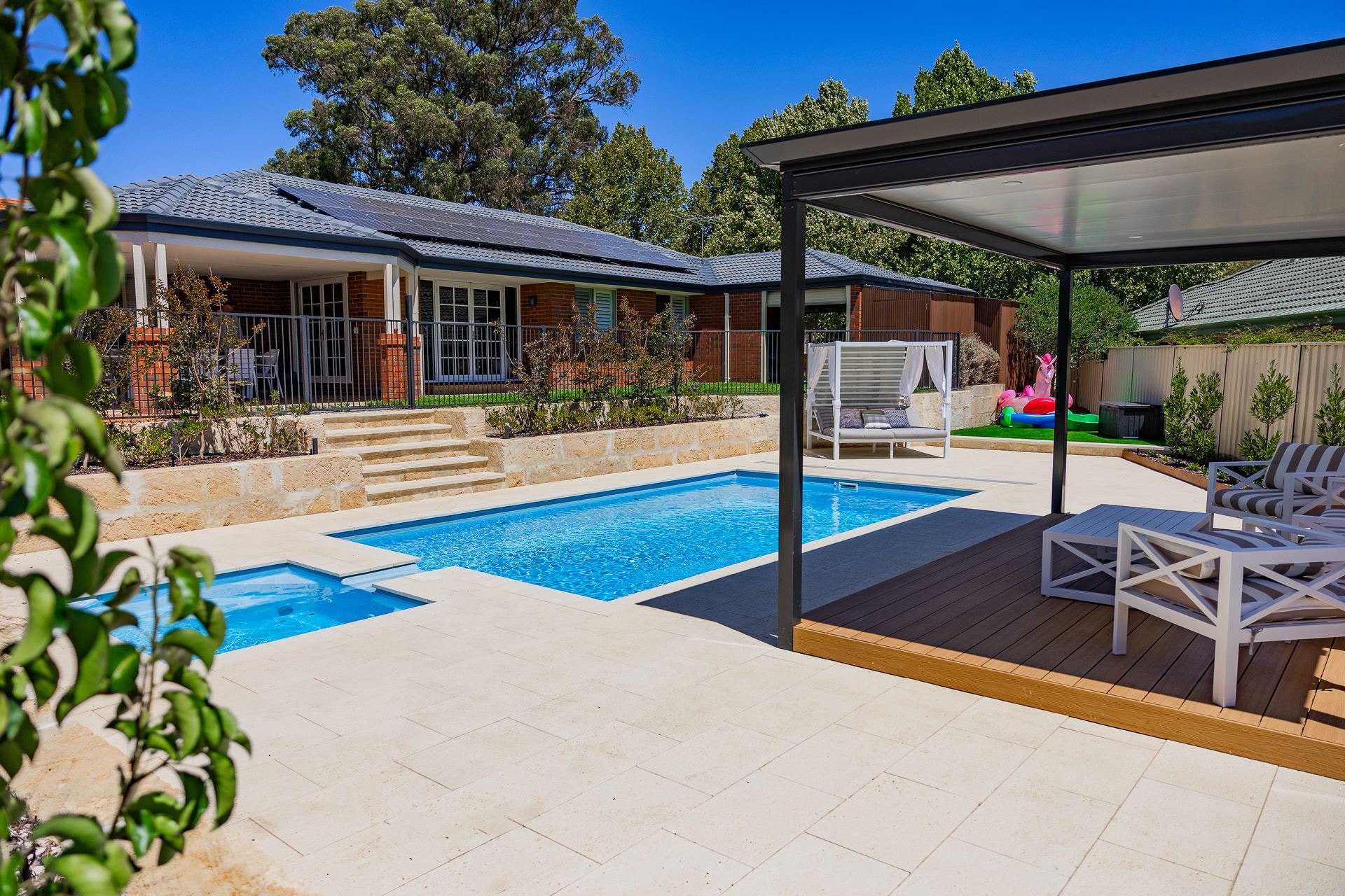 A pool seen through a pergola, with the house beyond
