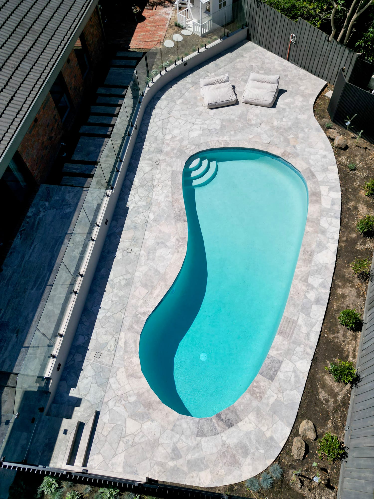 A freeform pool and paved surround from above