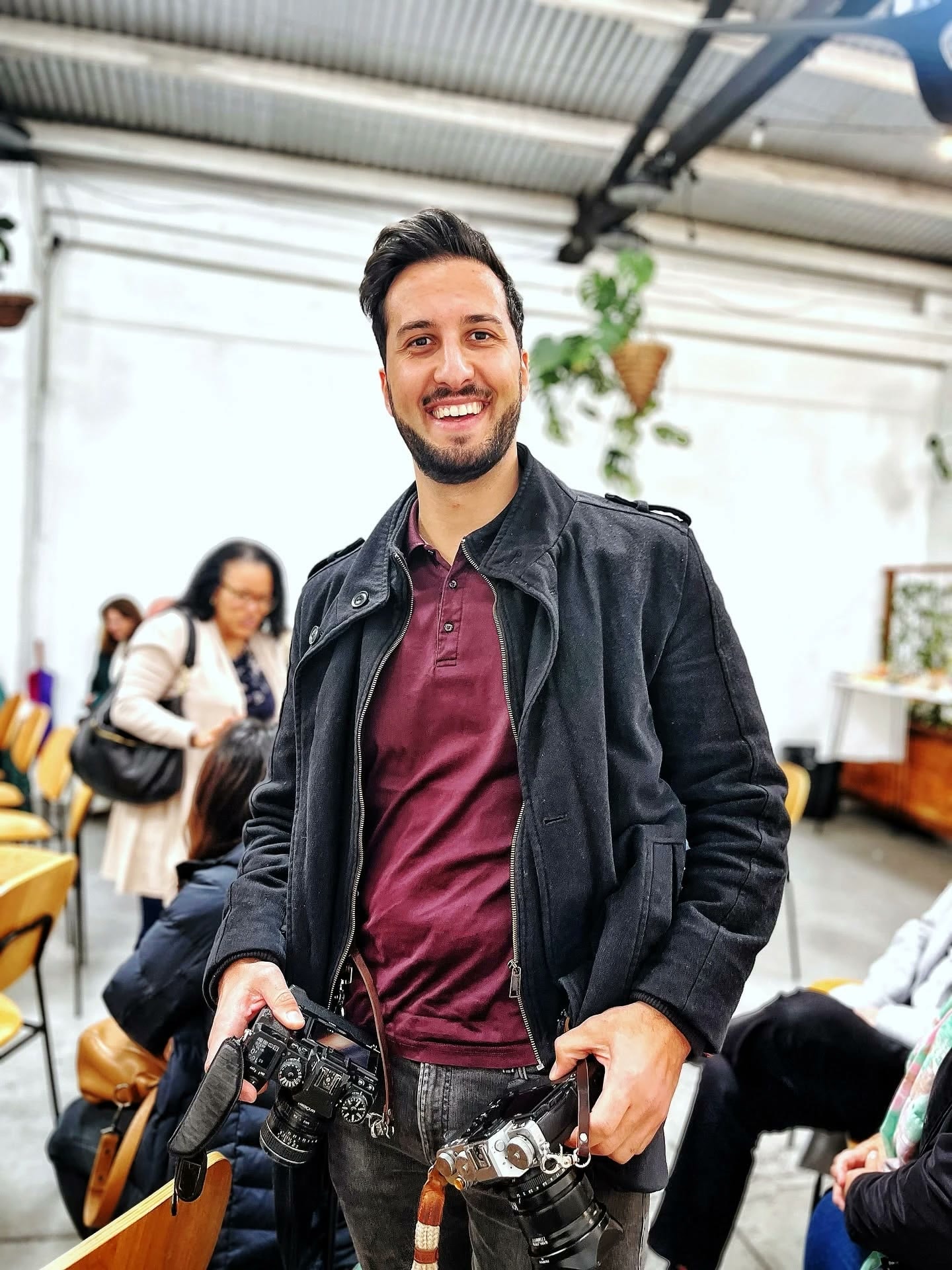 A smiling photographer holding two cameras at an event