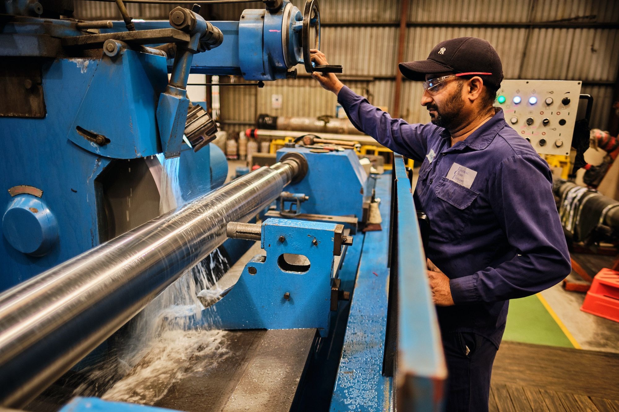 A machinist at a lathe with coolant spraying
