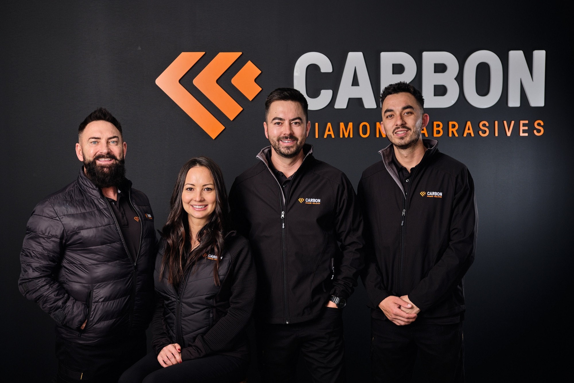 A team in front of their company sign