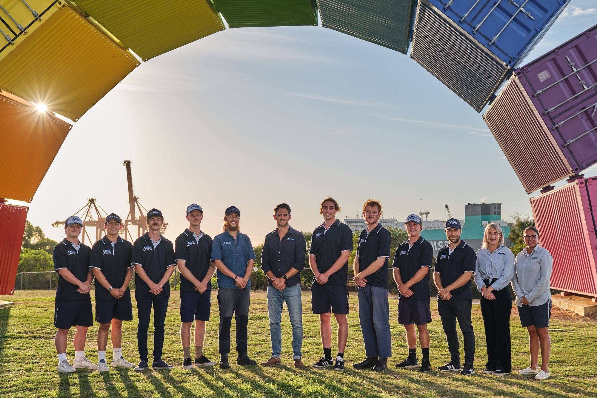 A trade team standing beneath an arch of coloured shipping containers