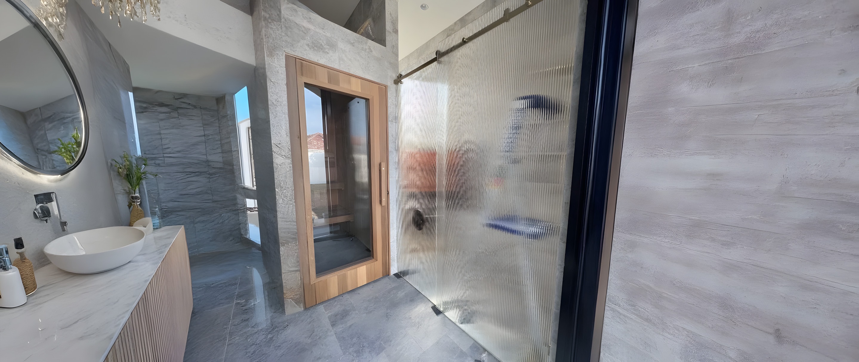 A stone bathroom with a fluted-glass shower screen beside a sauna